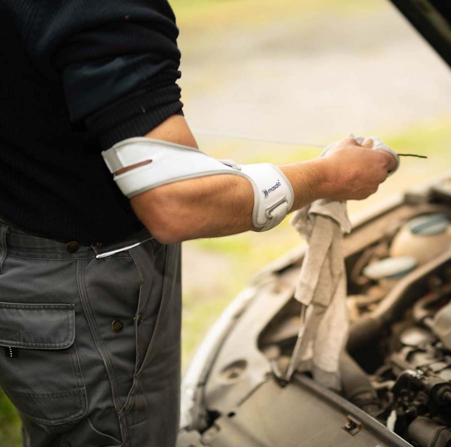 Mechaniker beim Ölwechsel am Auto mit Masalo Manschette gegen Tennisarm