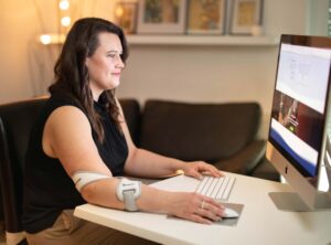 Woman working with a computer, wearing the masalo cuff against tennis elbow, golfer's elbow, mouse arm, RSI