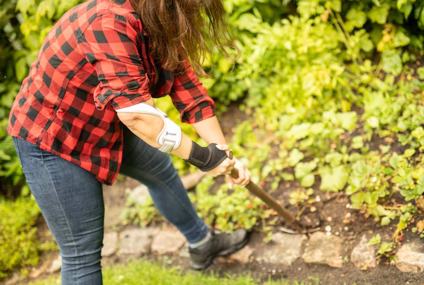 Frau bei der Gartenarbeit mit Masalo Manschette MED und Masalo Handgelenkbandage gegen Tennisarm, Golferarm, Epicondylitis